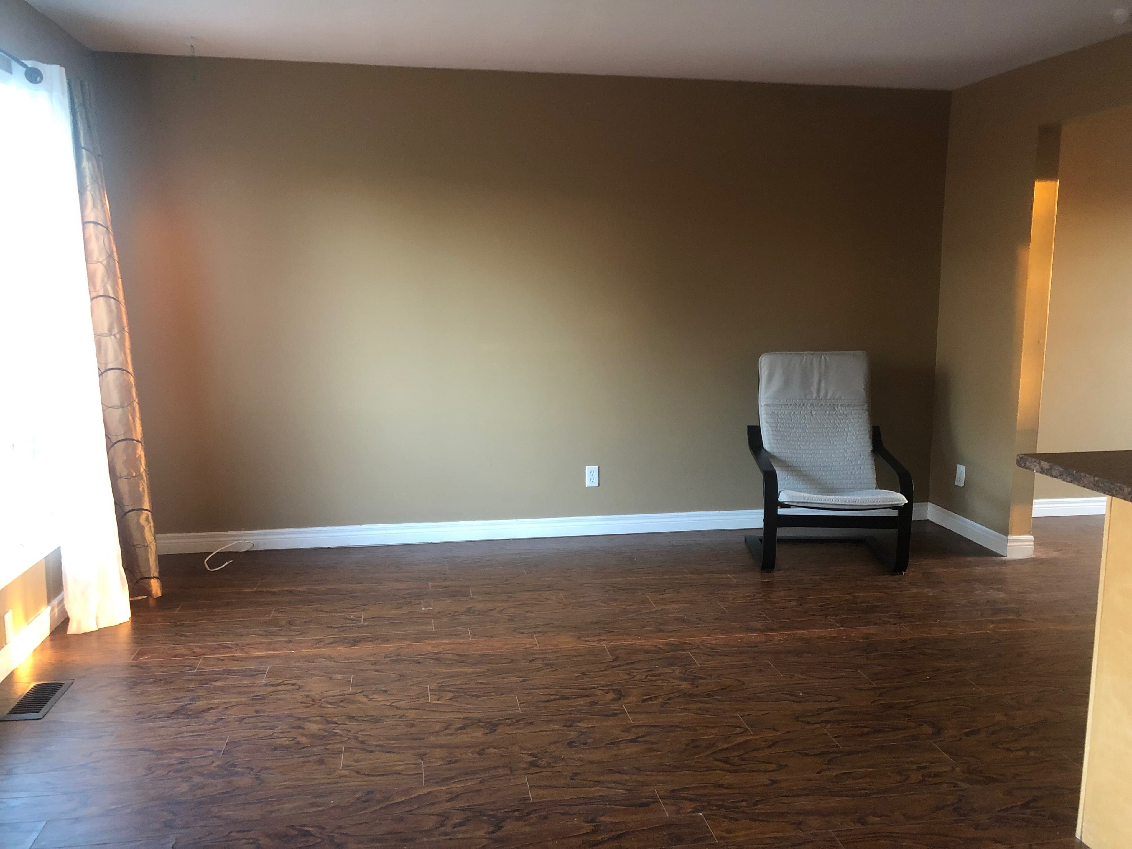 A nearly empty living room with one chair left by the wall